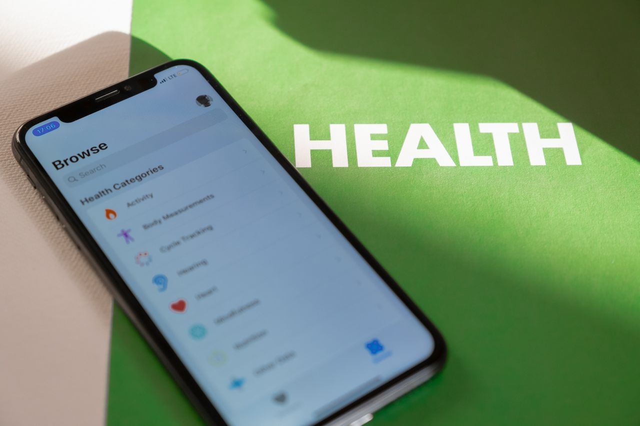 hero-img-01 Close-up of a smartphone displaying a health app on a green surface with 'HEALTH' text.