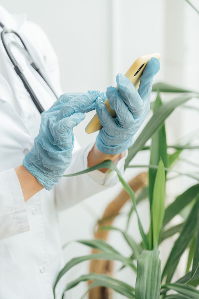 gallery-5 Doctor wearing gloves texts on smartphone, emphasizing healthcare and technology.