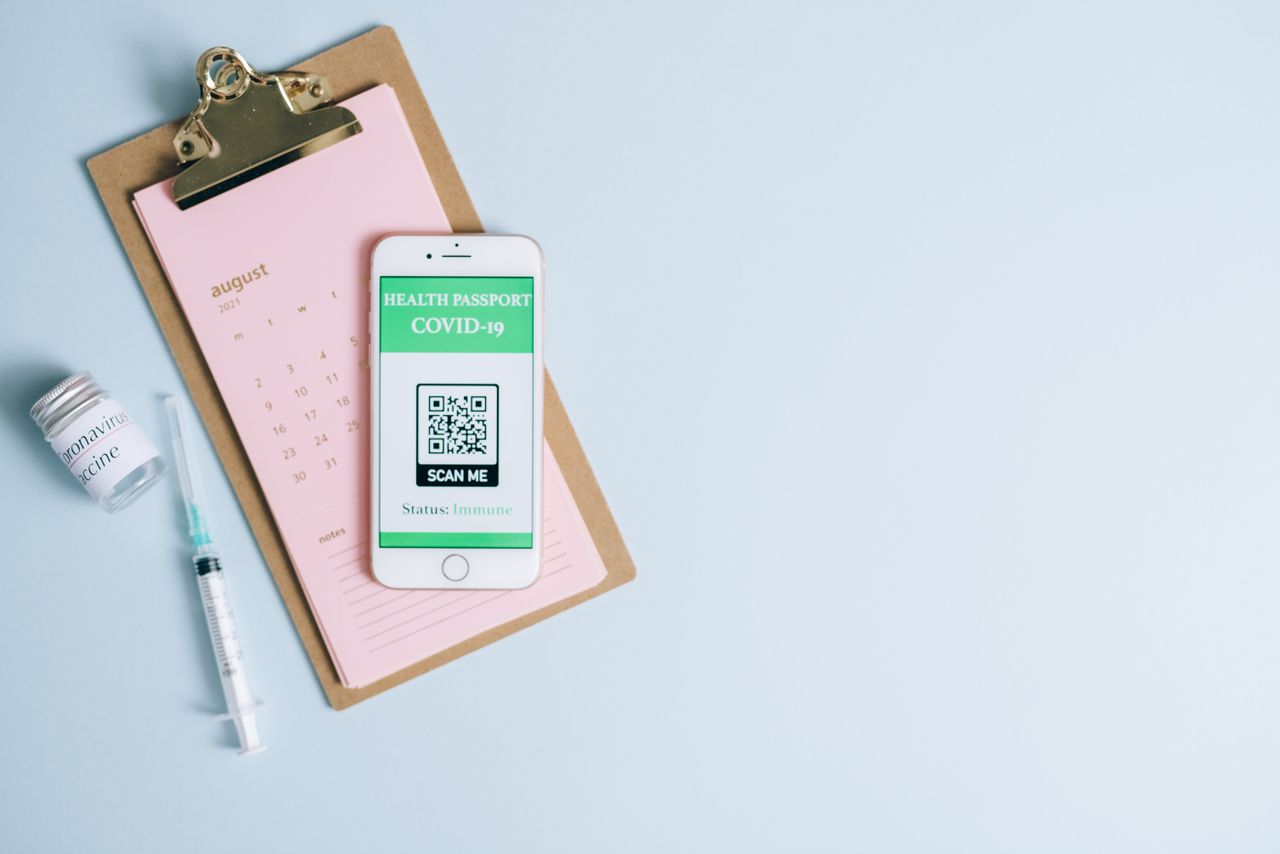 gallery-3 Flat lay image of COVID-19 health passport on a smartphone alongside a syringe and vaccine vial.