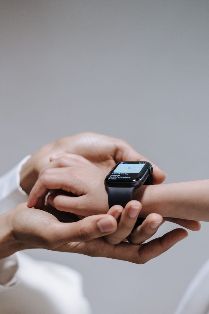 services-02 Close-up of a parent helping a child use a smartwatch, emphasizing digital connectivity and support.