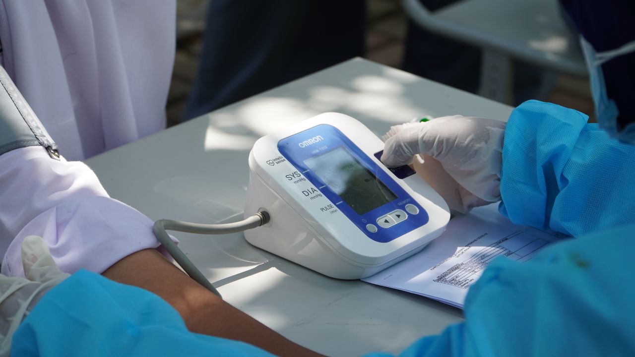 gallery-6 Healthcare worker checking patient's blood pressure with a digital device outdoors.